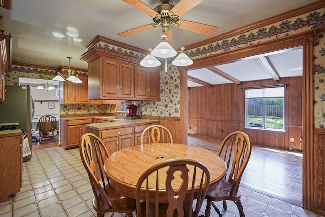 dining area featuring wood walls, a wainscoted wall, a ceiling fan, wallpapered walls, and light floors