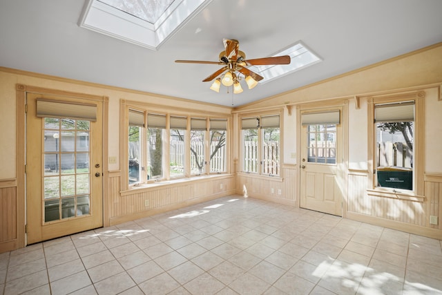unfurnished sunroom with tile patterned floors, a wainscoted wall, and lofted ceiling with skylight