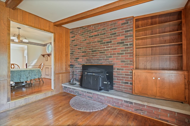 unfurnished living room with wood walls, beam ceiling, and hardwood / wood-style flooring