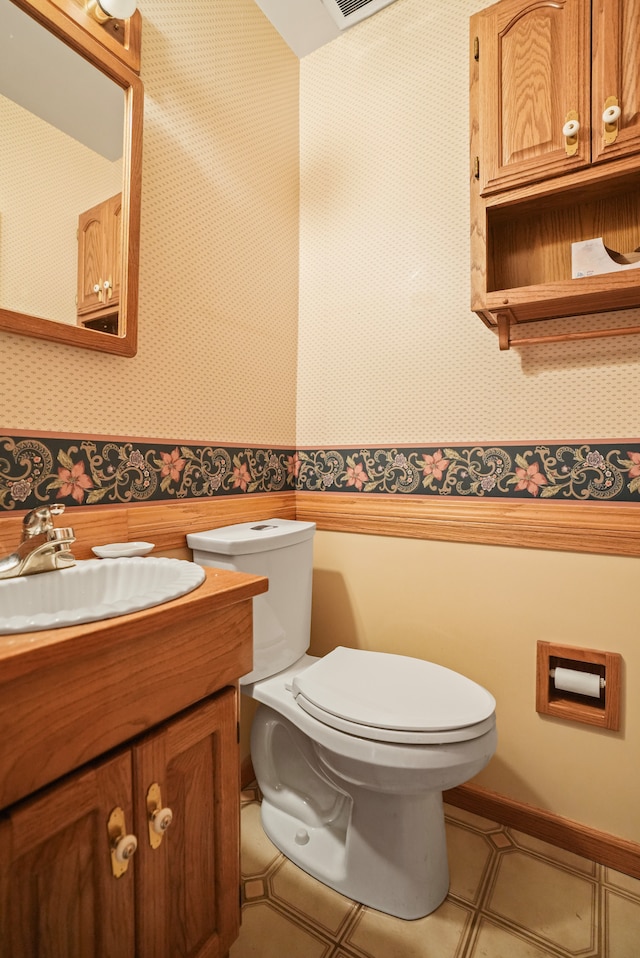 bathroom featuring vanity, toilet, and wallpapered walls