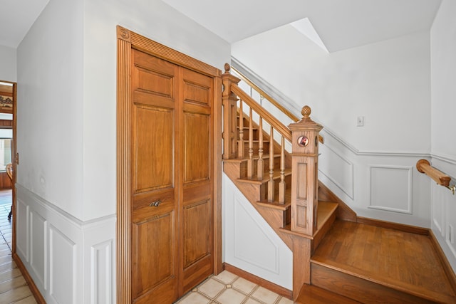 stairway featuring a wainscoted wall and a decorative wall