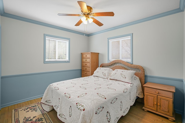 bedroom featuring a ceiling fan, ornamental molding, and light wood-style floors