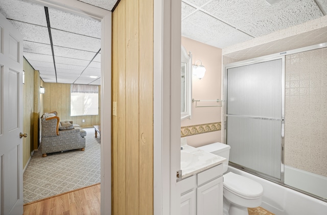 full bathroom featuring enclosed tub / shower combo, toilet, wood finished floors, and a paneled ceiling