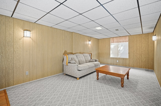 carpeted living room with visible vents, a drop ceiling, and wooden walls