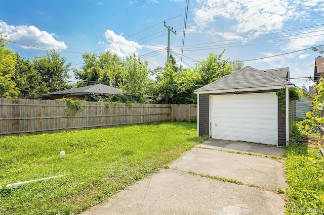 detached garage with concrete driveway and fence