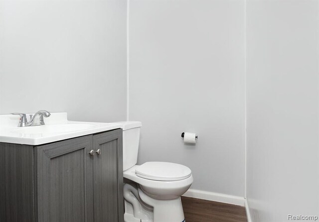 bathroom featuring toilet, wood finished floors, vanity, and baseboards