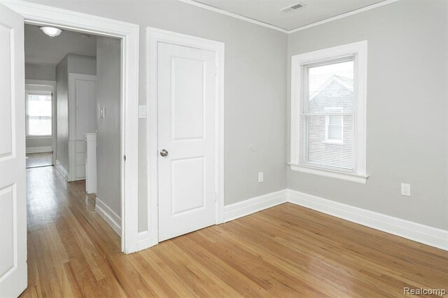 interior space featuring a wealth of natural light, crown molding, visible vents, light wood-style flooring, and baseboards