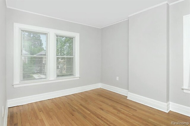 spare room featuring baseboards, ornamental molding, and light wood finished floors