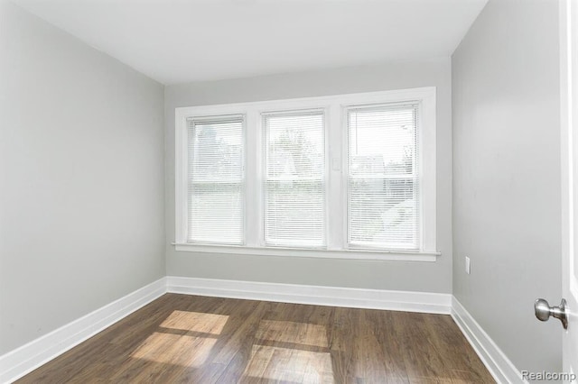 unfurnished room featuring dark wood-type flooring and baseboards