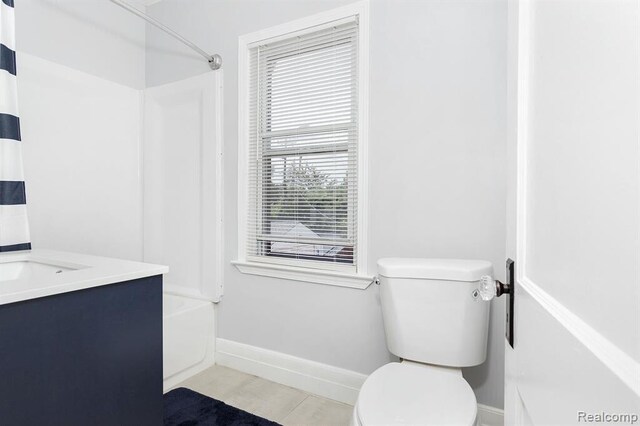 bathroom featuring toilet, shower / bathtub combination, vanity, and baseboards