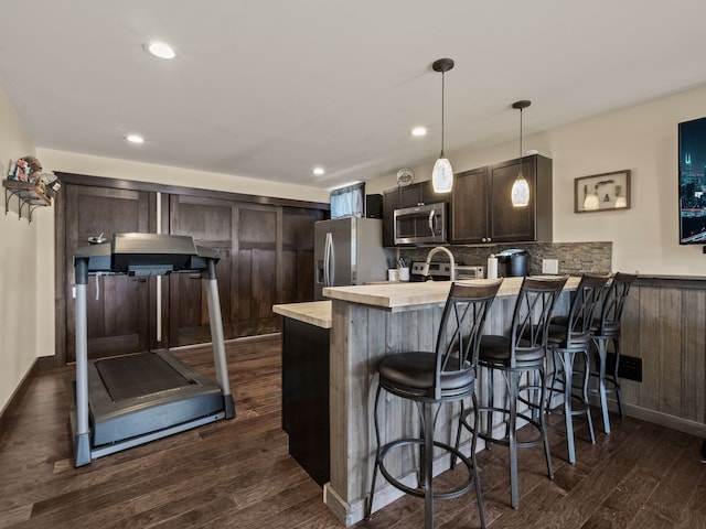 3190 Edgewood Park Dr, Commerce Twp, MI 48382 - kitchen featuring dark wood-style flooring, a peninsula, dark brown cabinetry, a breakfast bar, and stainless steel appliances