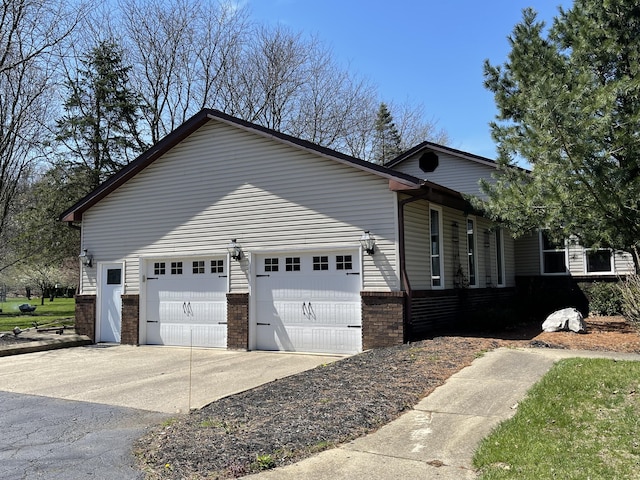 331 Jonesville Rd, Jonesville, MI 49250 - view of home's exterior with brick siding, a garage, and driveway