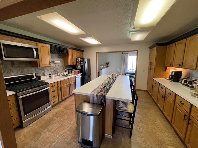 331 Jonesville Rd, Jonesville, MI 49250 - kitchen featuring light tile patterned flooring, a breakfast bar area, stainless steel appliances, decorative backsplash, and a kitchen island