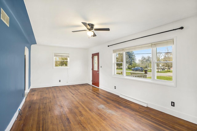 unfurnished room featuring ceiling fan, visible vents, plenty of natural light, baseboard heating, and baseboards