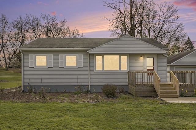 view of front facade featuring a deck, a shingled roof, and a lawn