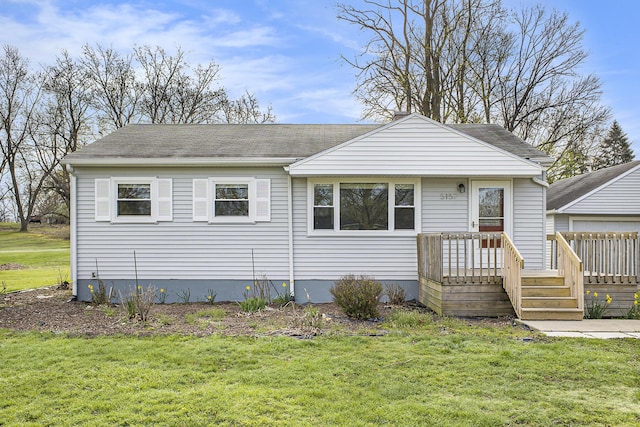 view of front of property featuring a wooden deck, a front yard, and roof with shingles