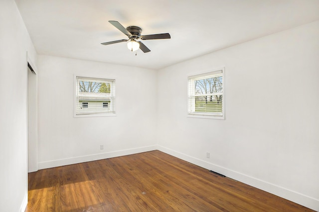 spare room with dark wood-style floors, a wealth of natural light, and baseboards