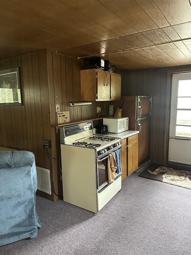 2934 River Ridge Rd, Alger, MI 48610 - kitchen with visible vents, white appliances, wooden walls, and carpet flooring