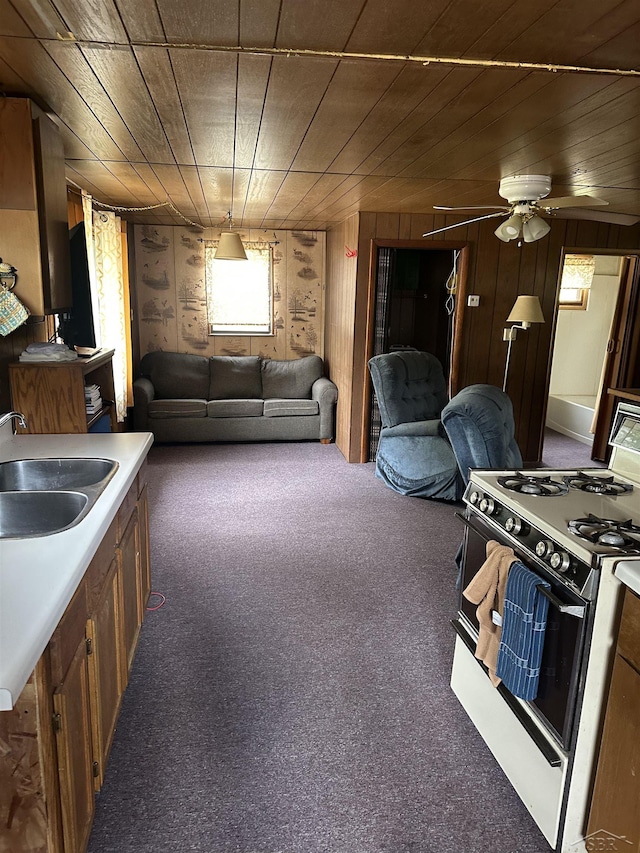 2934 River Ridge Rd, Alger, MI 48610 - kitchen with carpet flooring, a sink, a ceiling fan, wood walls, and range with gas cooktop