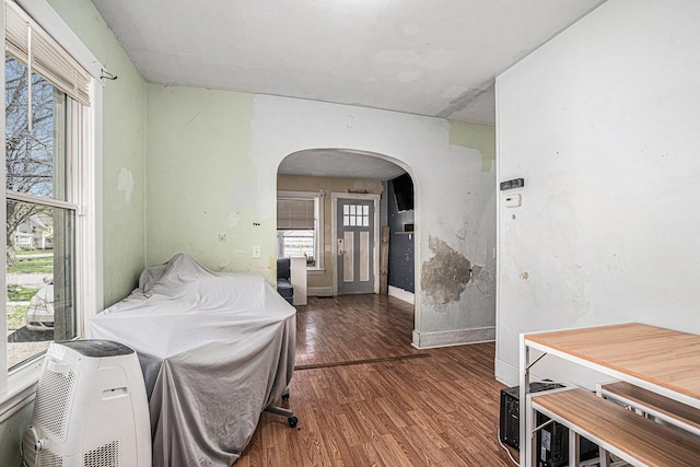 foyer with wood finished floors, a healthy amount of sunlight, baseboards, and arched walkways