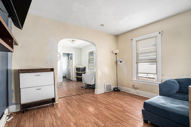 sitting room with arched walkways, visible vents, wood finished floors, and baseboards