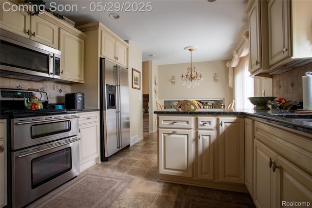 140 Indian Knolls St, Oxford, MI 48371 - kitchen featuring stainless steel appliances, cream cabinetry, a chandelier, a peninsula, and decorative backsplash