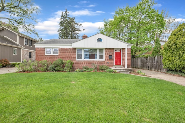 view of front of home with brick siding, fence, a chimney, and a front yard