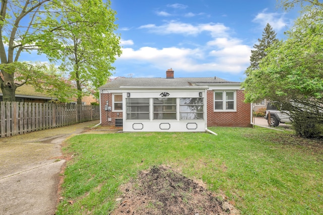 back of house with brick siding, fence, a yard, and a chimney