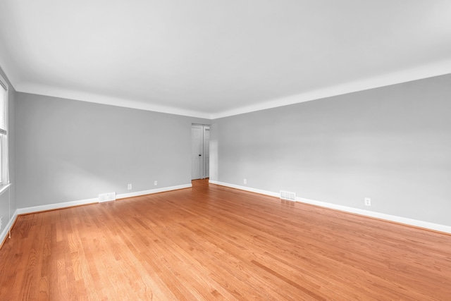 spare room with visible vents, baseboards, and wood finished floors