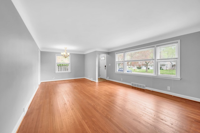 unfurnished living room with baseboards, light wood-type flooring, a chandelier, and visible vents