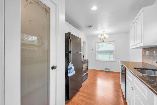 kitchen with an inviting chandelier, black appliances, a sink, and white cabinetry