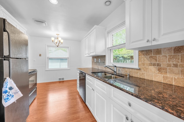 kitchen featuring visible vents, freestanding refrigerator, a sink, light wood finished floors, and dishwasher