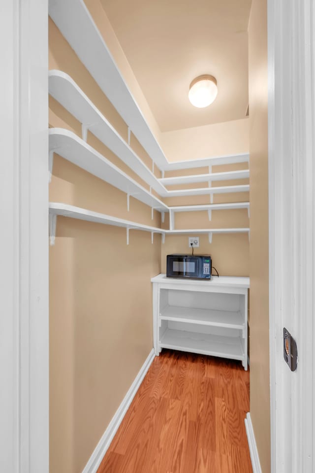 walk in closet with wood finished floors