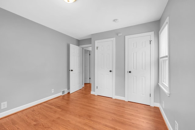 unfurnished bedroom featuring baseboards, visible vents, and light wood-style flooring