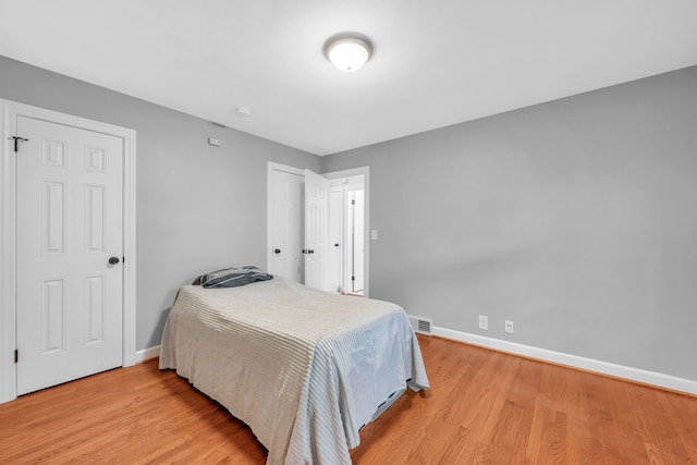 bedroom with visible vents, light wood-style flooring, and baseboards