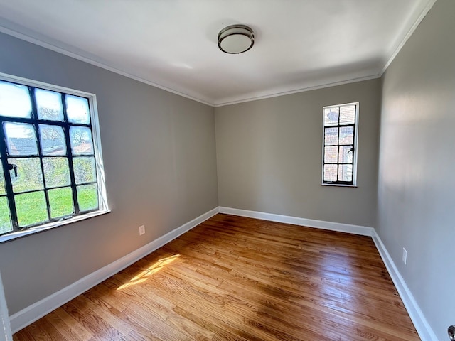 spare room featuring crown molding, light wood finished floors, and baseboards