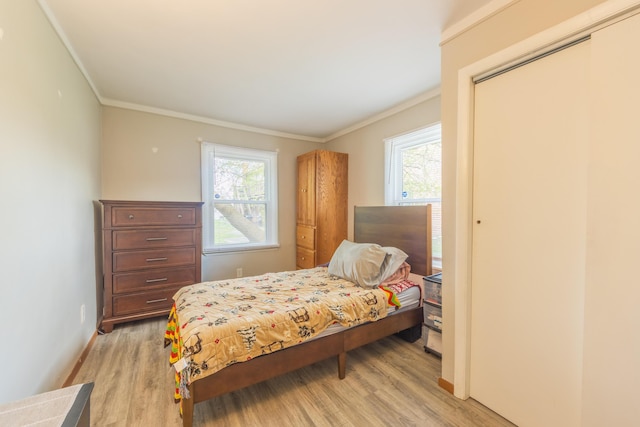 bedroom featuring light wood-style floors, ornamental molding, and multiple windows