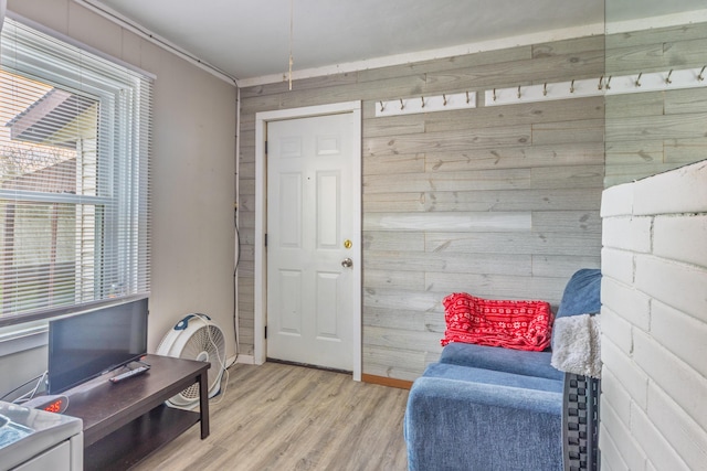 sitting room featuring wooden walls, light wood-style flooring, and baseboards