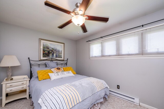 carpeted bedroom with a baseboard heating unit, a ceiling fan, and baseboards