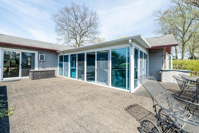 back of property featuring a sunroom, a shingled roof, and a patio area