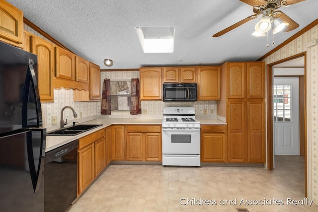 kitchen with a sink, light countertops, wallpapered walls, black appliances, and light floors