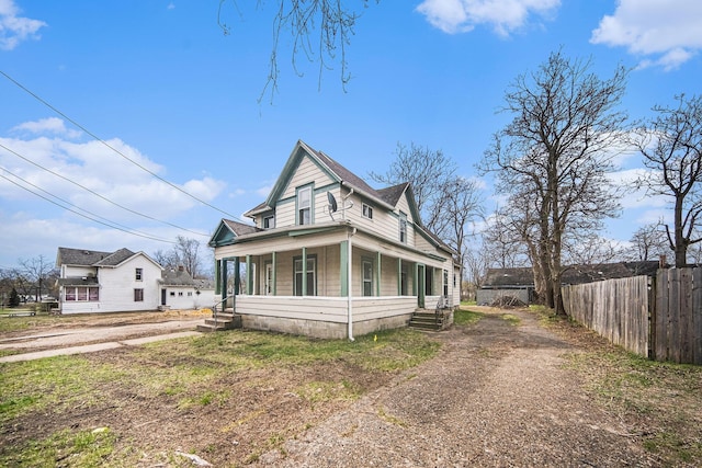 view of front of house with fence, covered porch, and dirt driveway