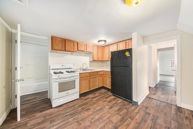 kitchen featuring gas range gas stove, freestanding refrigerator, light countertops, dark wood-style flooring, and a sink