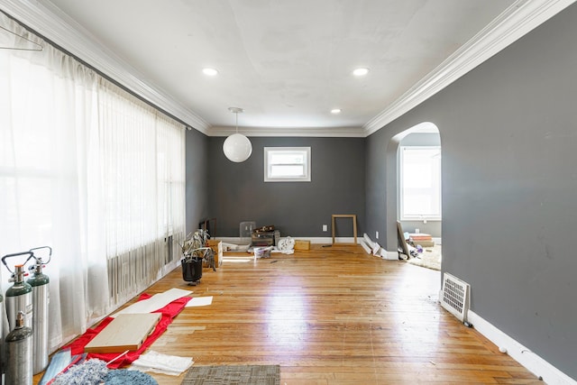 interior space with wood-type flooring, visible vents, ornamental molding, arched walkways, and baseboard heating