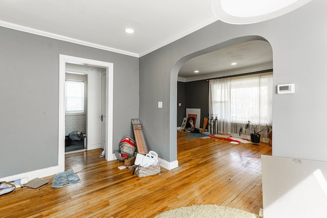 interior space with hardwood / wood-style floors, a wealth of natural light, crown molding, and arched walkways