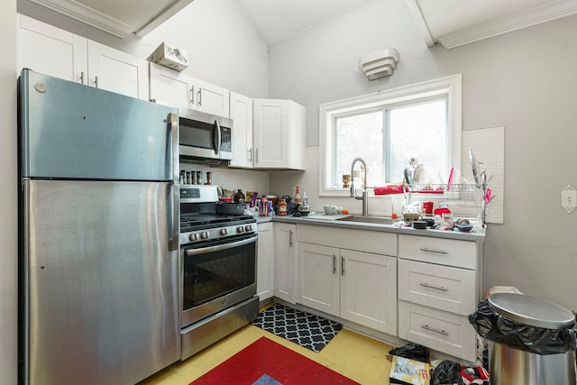 kitchen featuring a sink, tasteful backsplash, crown molding, white cabinetry, and appliances with stainless steel finishes