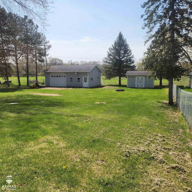 view of yard featuring fence, a shed, an outdoor structure, and a garage