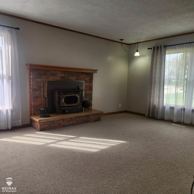 unfurnished living room featuring crown molding, a wood stove, a textured ceiling, and carpet flooring