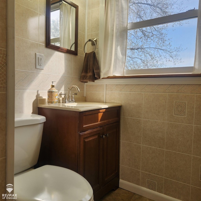 bathroom with tile walls, tile patterned flooring, vanity, and toilet