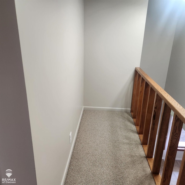 hallway featuring baseboards and light carpet
